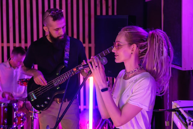 A girl holding a microphone and a man playing a guitar. 