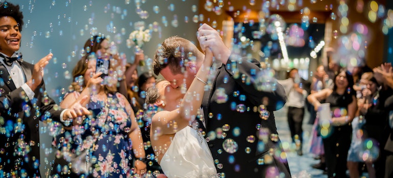 Newly wedded couple kissing surrounded by bubbles.