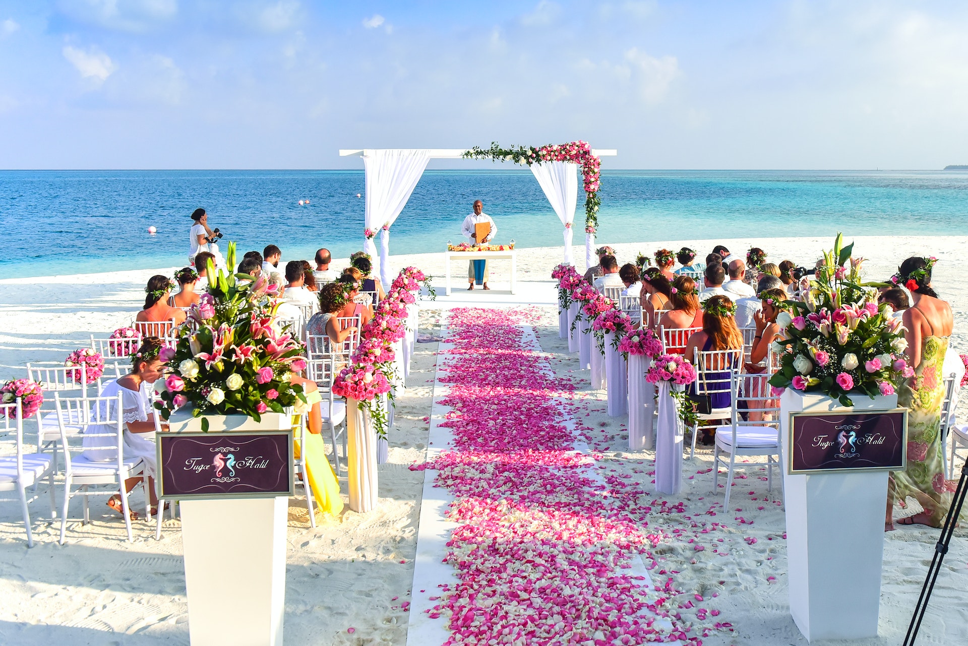 A beach wedding decorated with pink flowers.