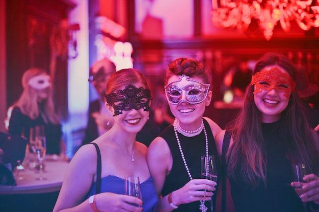 Three women wearing masks at a themed corporate event.