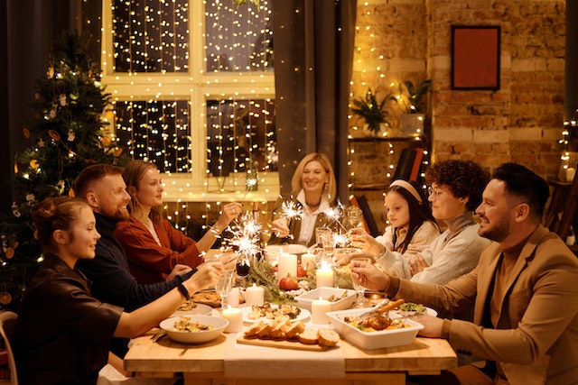 family at a Christmas party having dinner and holding burning sprinklers