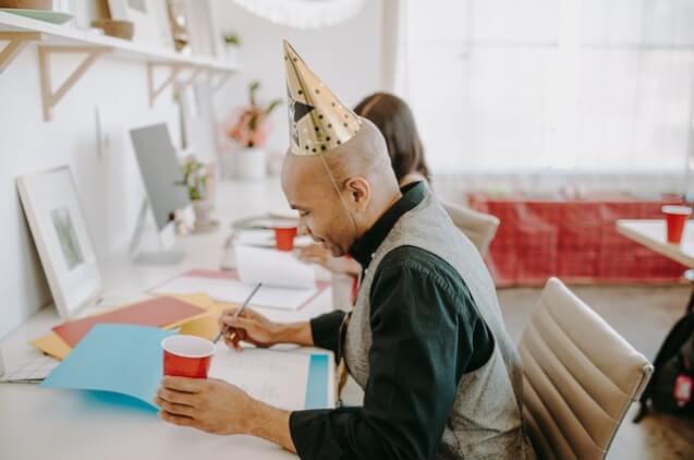 People in an office wearing party hats during event planning at the workspace.