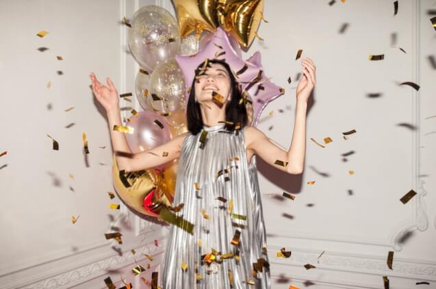 A woman looking at falling confetti.