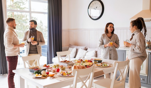 People talking around a table full of food as the hosts followed the event party checklist.